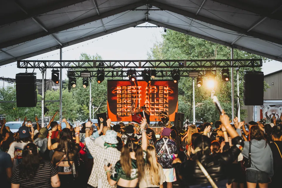 Brett Allen performing under the tent with his name on the LED wall and a crowd cheering